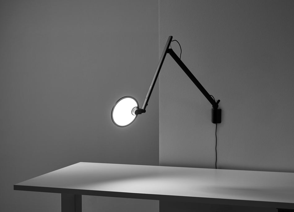 Lampe de bureau Humanscale Nova noire fixée par pince, tête orientée